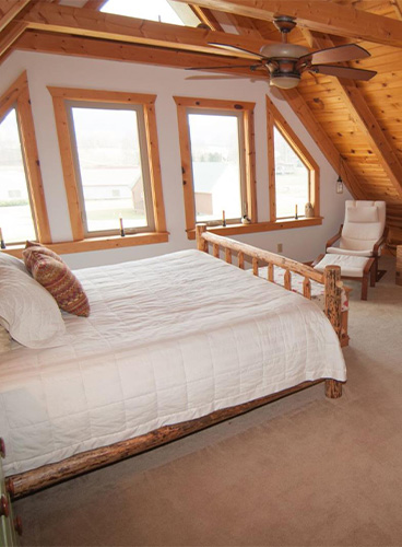 A master bedroom with a king-size bed, mountain views through large windows, and a cozy reading nook.